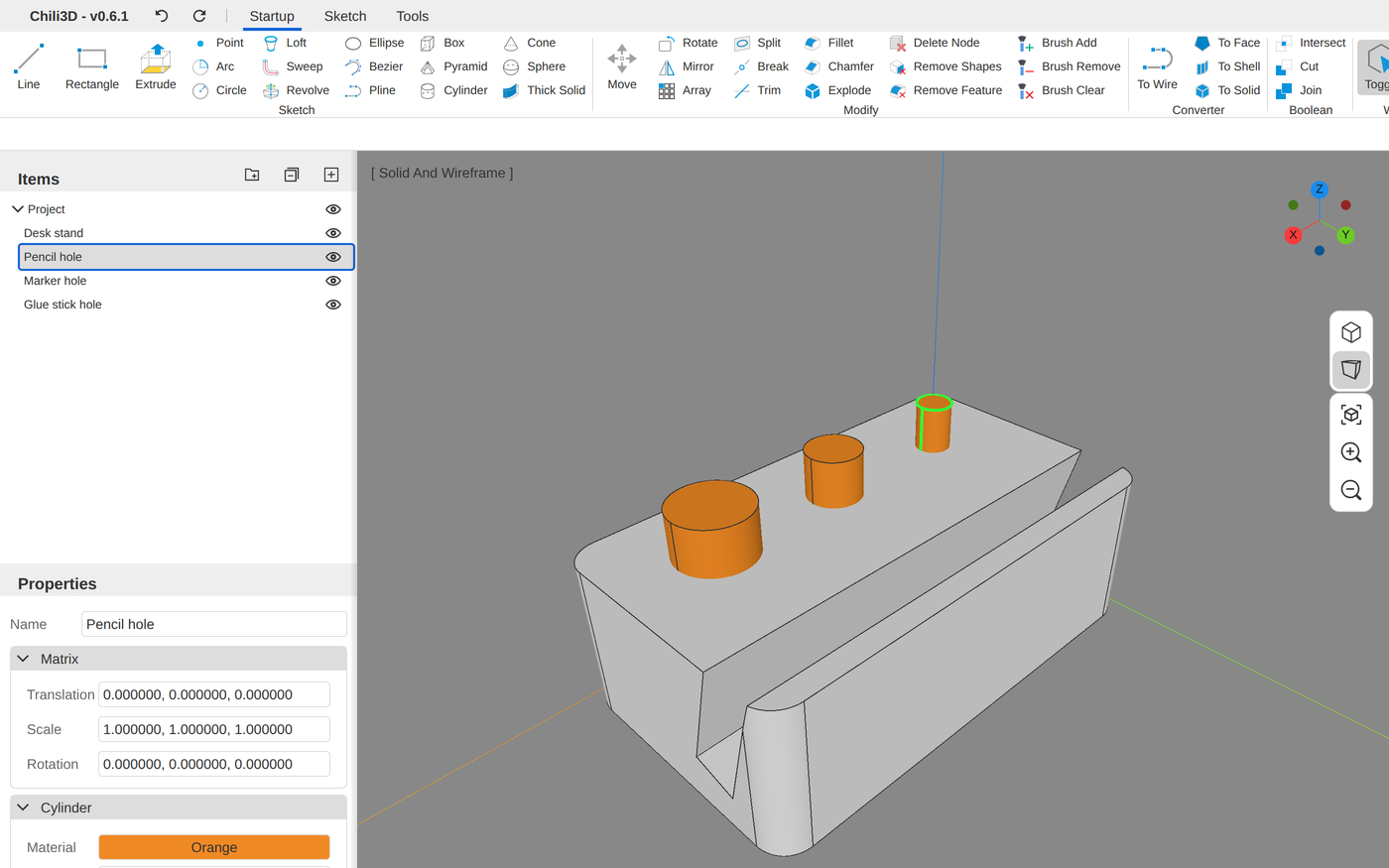 Chili3D with the desk stand loaded. A ribbon of modeling buttons runs across the top, in groups including Sketch, Modify, Converter and Boolean. In the 3D view, a light gray block with rounded corners has a slot along one long side for a phone, and three orange cylinders of different widths stand up out of its top in a row. The Items panel on the left lists Desk stand, Pencil hole, Marker hole and Glue stick hole, with Pencil hole selected, and the Properties panel below it shows that cylinder's settings.